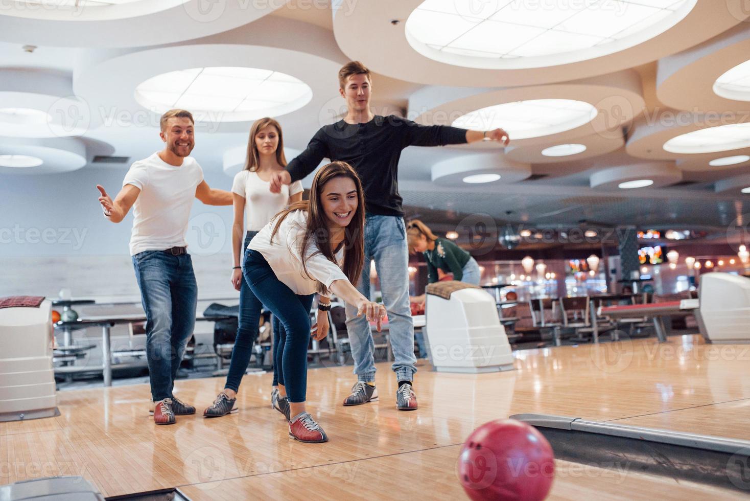 kom op je kan het. jonge vrolijke vrienden hebben plezier in de bowlingclub in hun weekenden foto