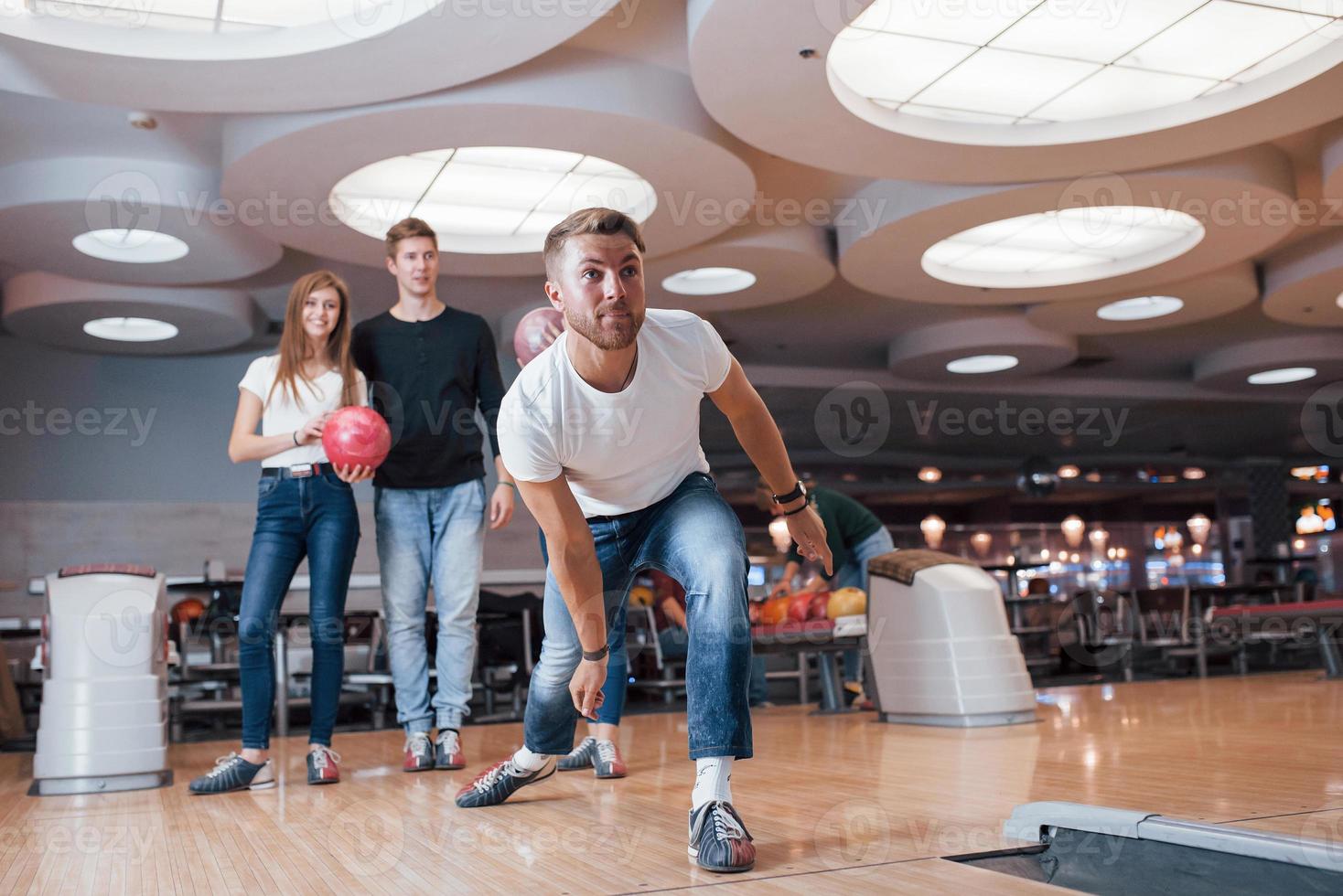 sportconcept. jonge vrolijke vrienden hebben plezier in de bowlingclub in hun weekenden foto