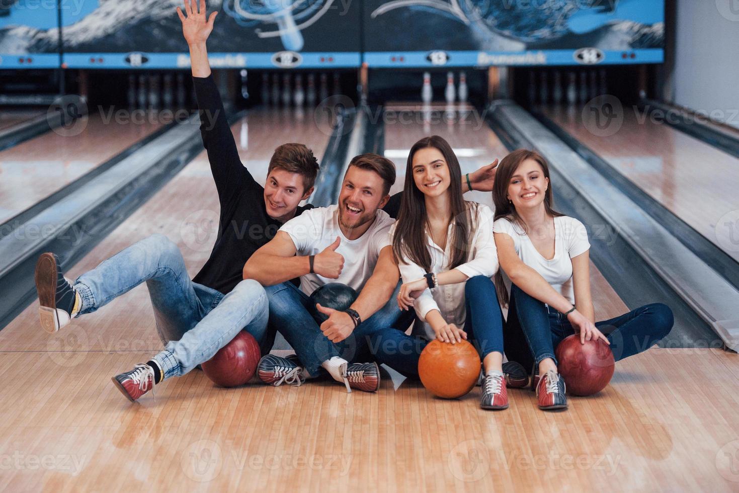 man veel plezier met opgeheven armen. jonge vrolijke vrienden hebben plezier in de bowlingclub in hun weekenden foto