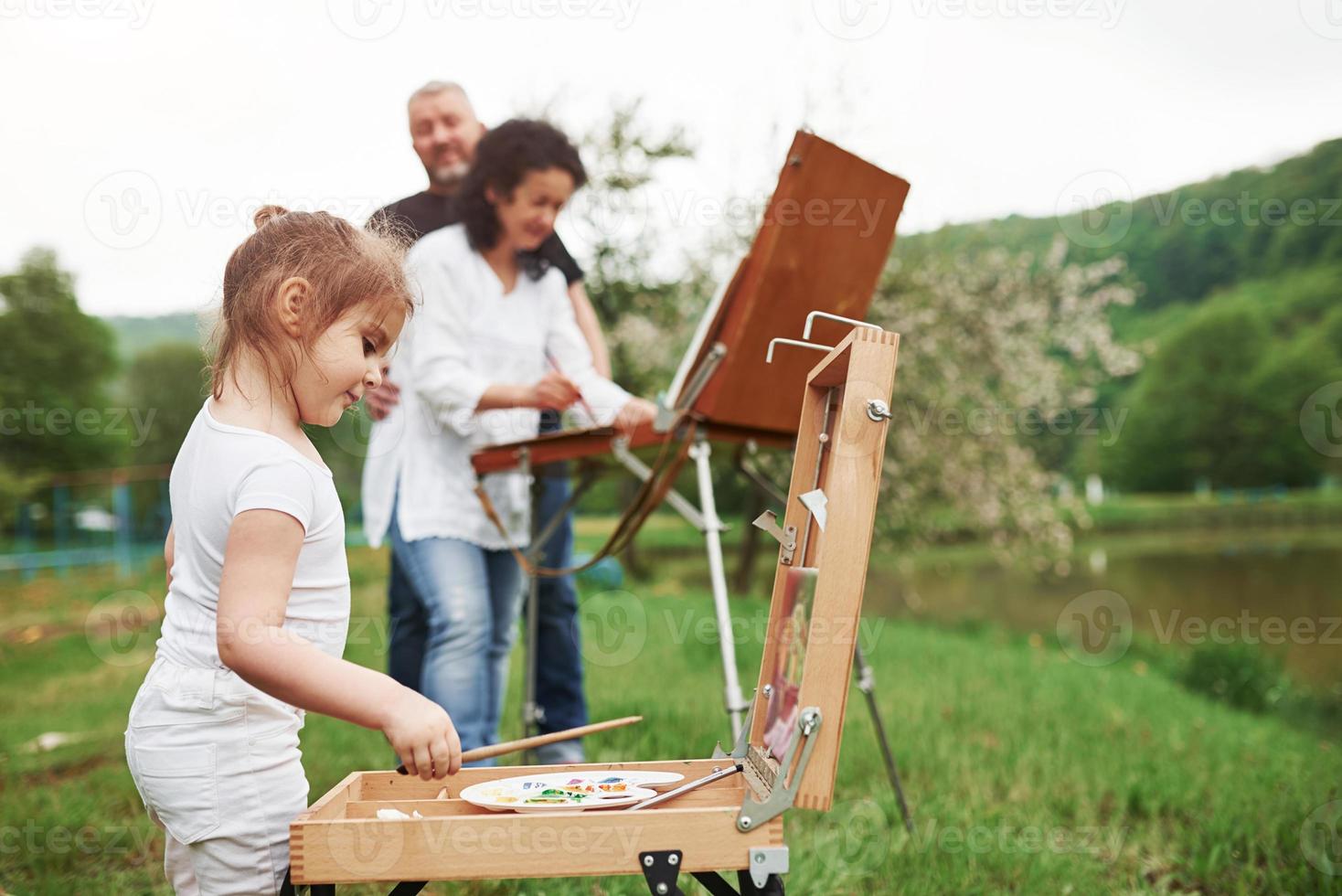 bewolkt weer. oma en opa hebben plezier buiten met kleindochter. schilderij conceptie foto