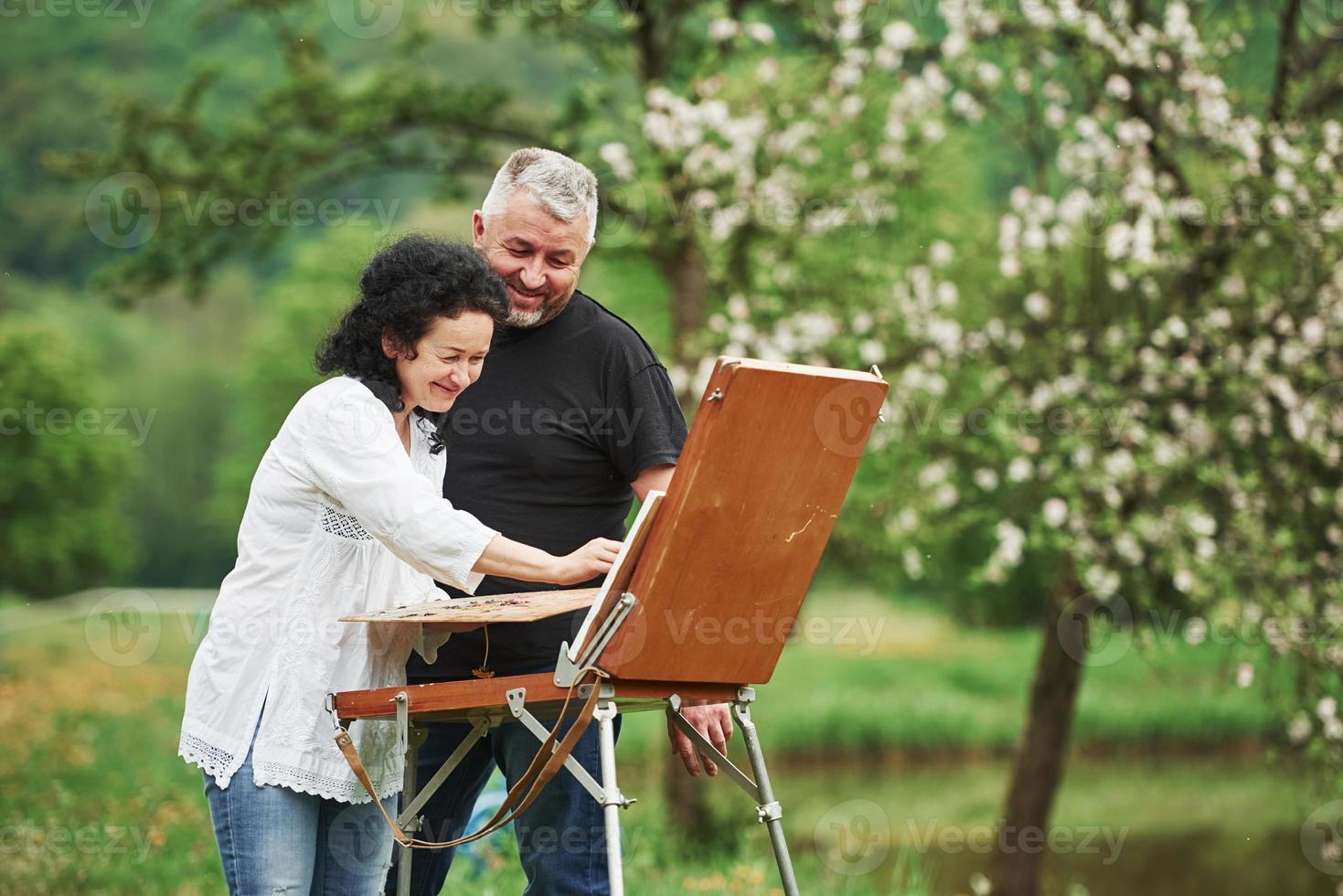 lachen en plezier hebben. volwassen stel heeft vrije dagen en werkt samen aan de verf in het park foto