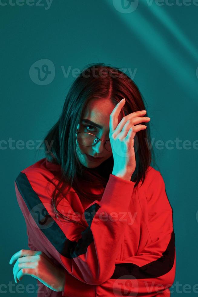 voorzichtig looks Bij jij. studio schot binnenshuis met neon licht. portret van mooi jong meisje foto