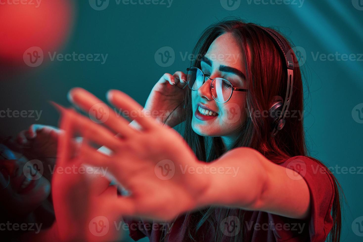 genieten van muziek. studio schot binnenshuis met neon licht. portret van mooi jong meisje foto