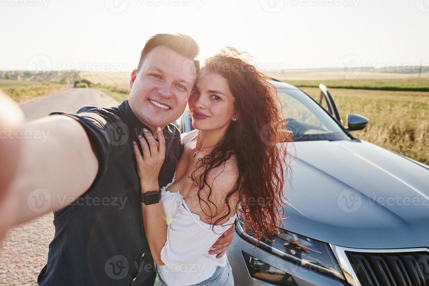 nemen selfie. lief paar in de buurt hun nieuw modern auto Bij weekend tijd foto