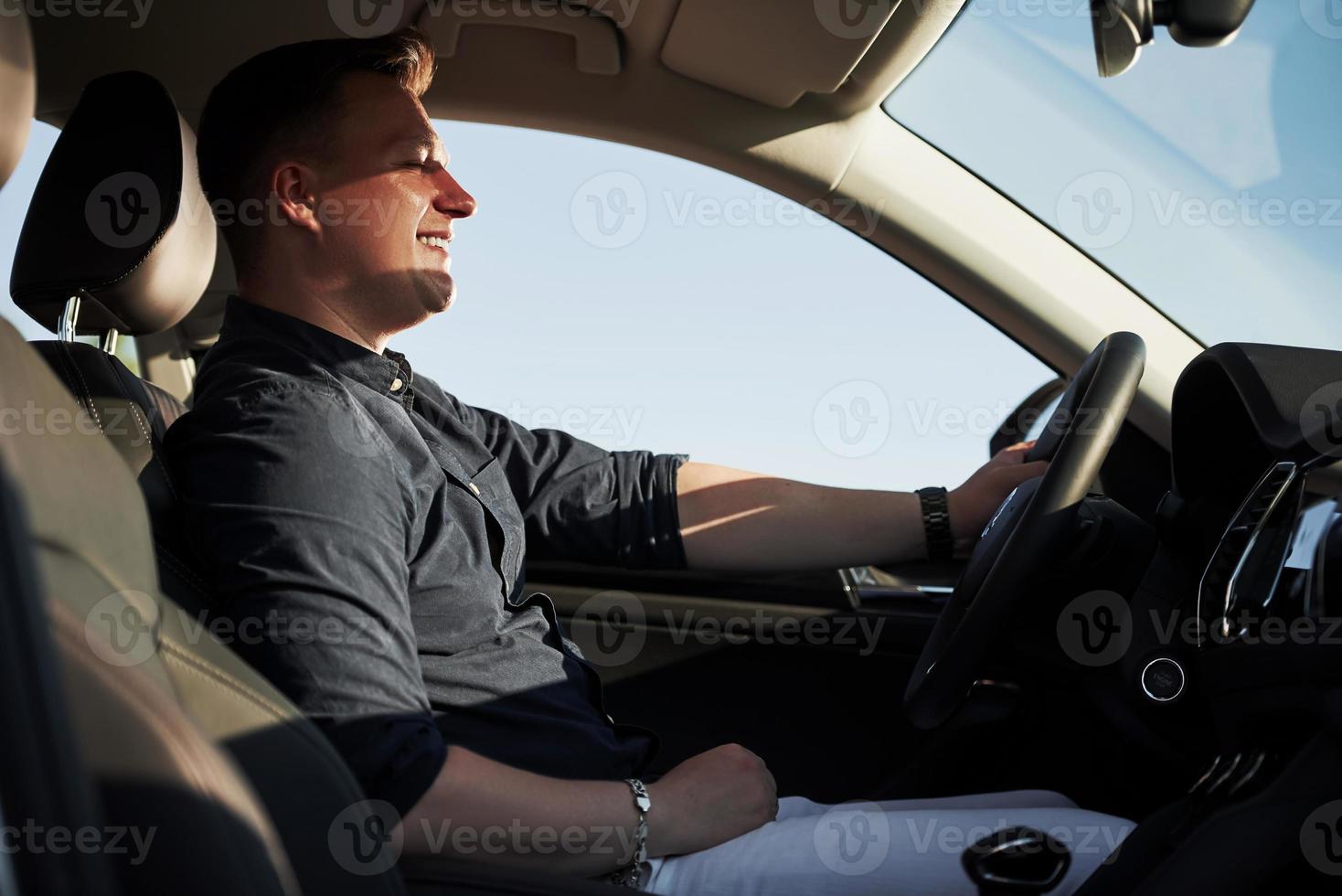 met ogen Gesloten. tevredenheid. bestuurder voelt mooi zo in zijn merk nieuw auto. rijden Bij zonnig dag foto