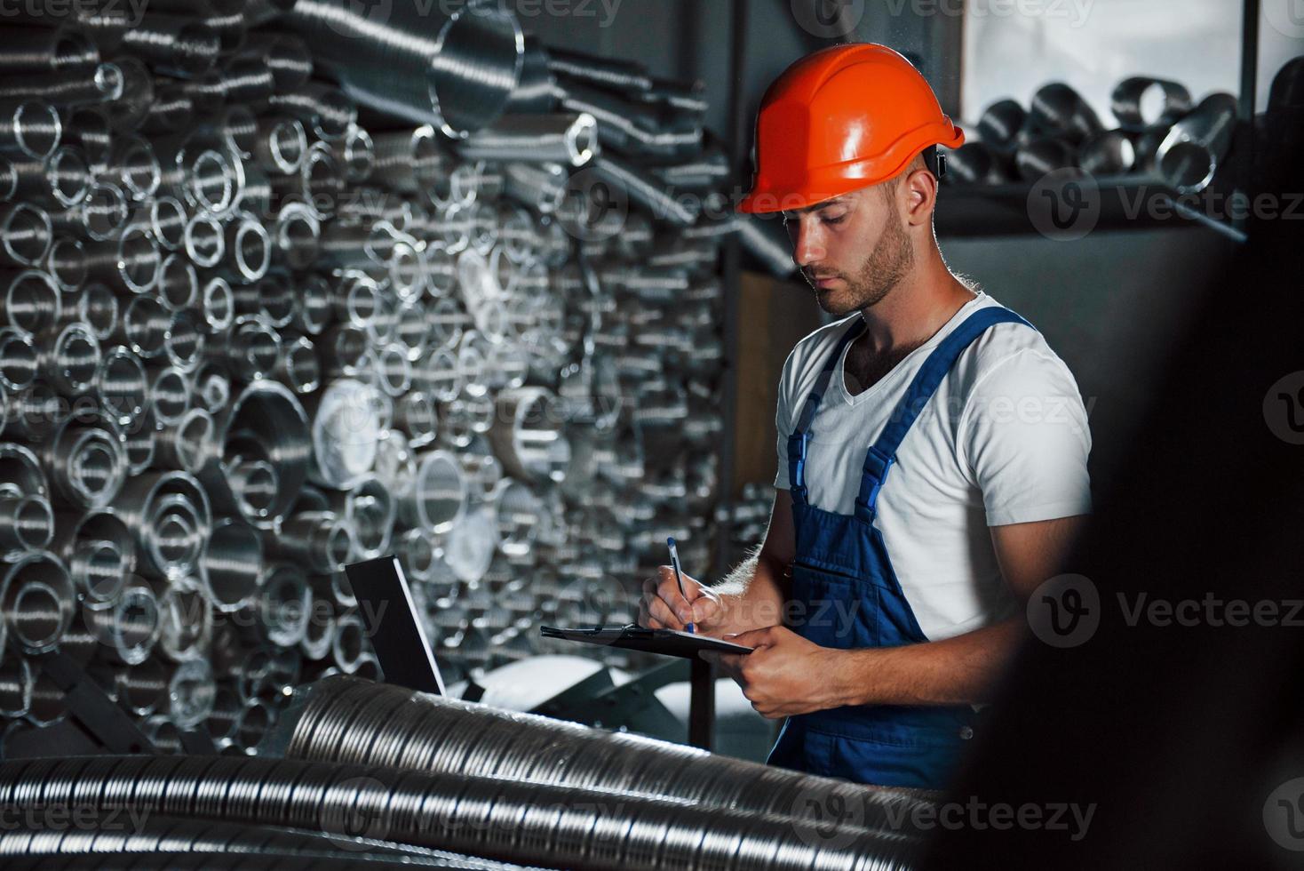 schrijven in kladblok. Mens in uniform werken Aan de productie. industrieel modern technologie foto