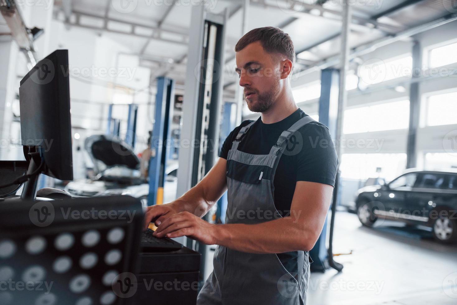 modern technologieën. Mens Bij de werkplaats in uniform gebruik computer voor zijn baan voor vaststelling gebroken auto foto