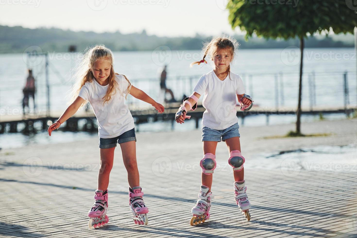 twee schattig kinderen rijden door rol skates in de park Bij dag foto