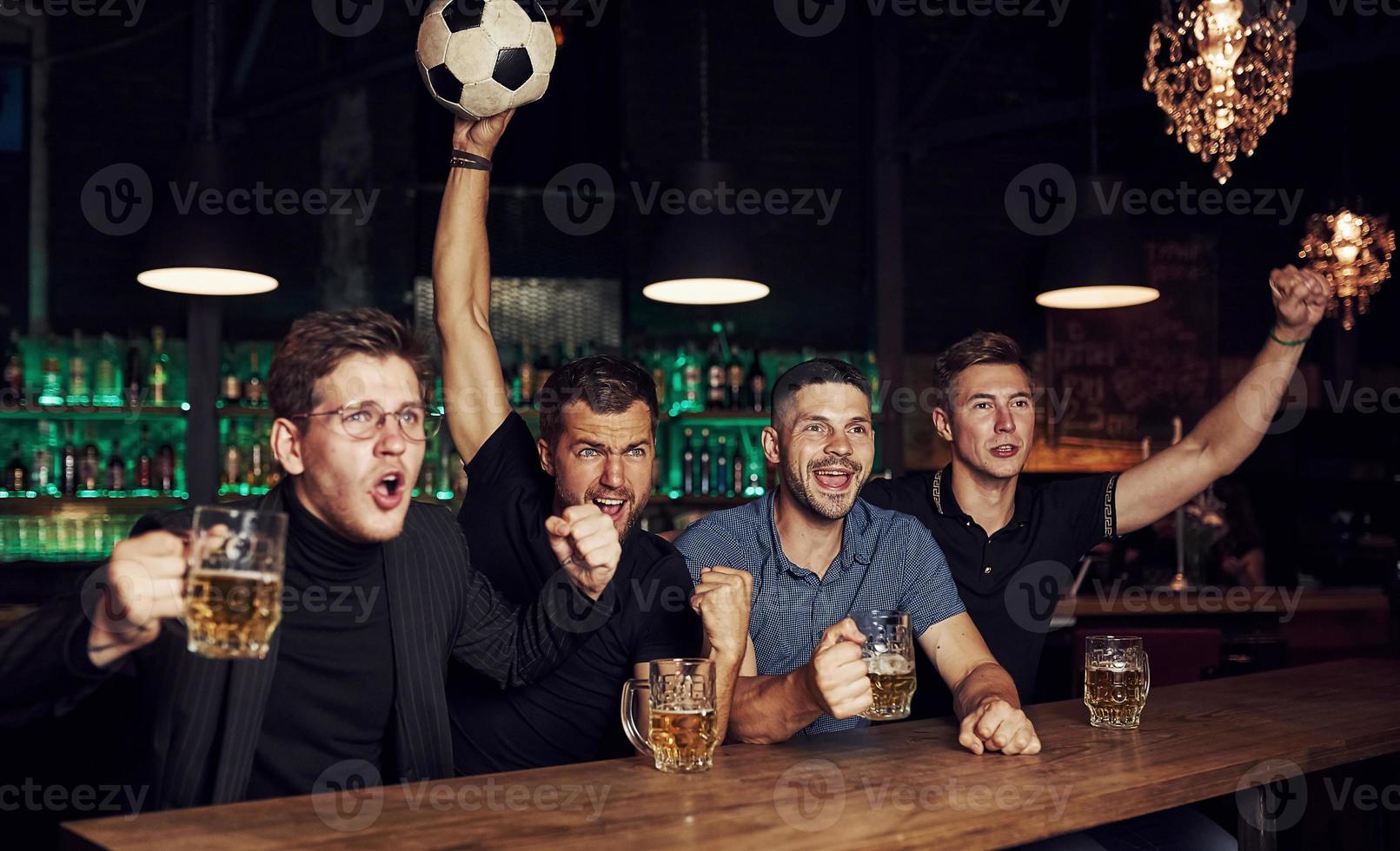 met voetbal bal. zijn een doel. vieren zege. drie sport- fans in een bar aan het kijken Amerikaans voetbal met bier in handen foto