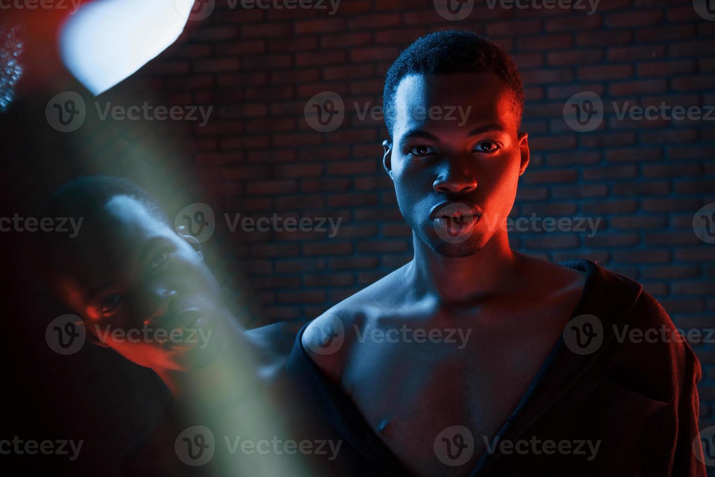 zelfverzekerd jongen. futuristische neon verlichting. jong Afrikaanse Amerikaans Mens in de studio foto