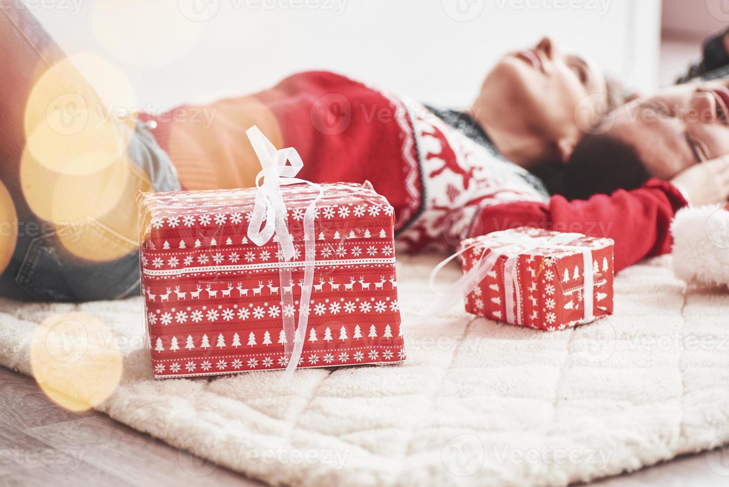 wij kan Tenslotte kom tot rust naar voelen vredig en vernieuwen. lief jong paar aan het liegen Aan de verdieping van leven kamer Bij nieuw jaar tijd met geschenk dozen foto