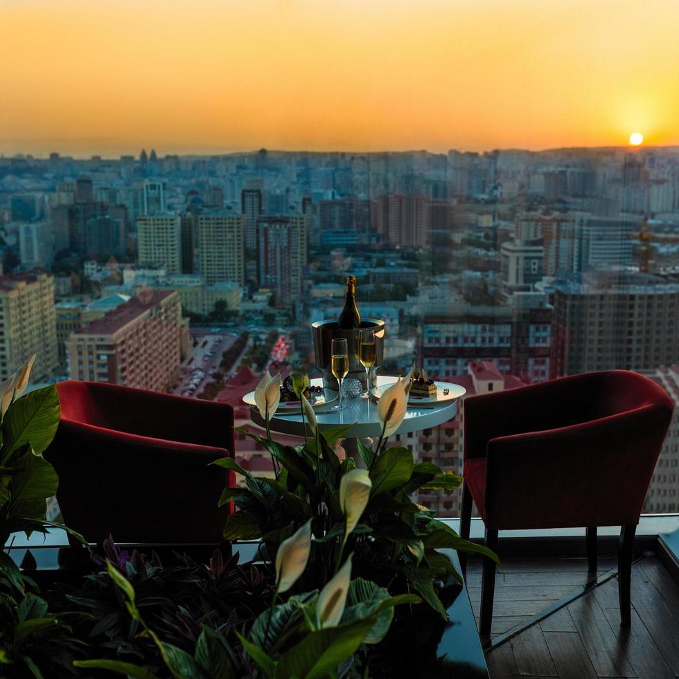 champagnefles en glazen in restaurant met uitzicht op de stad zonsondergang foto