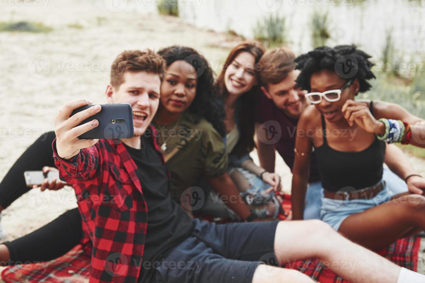 nemen selfie. groep van mensen hebben picknick Aan de strand. vrienden hebben pret Bij weekend tijd foto