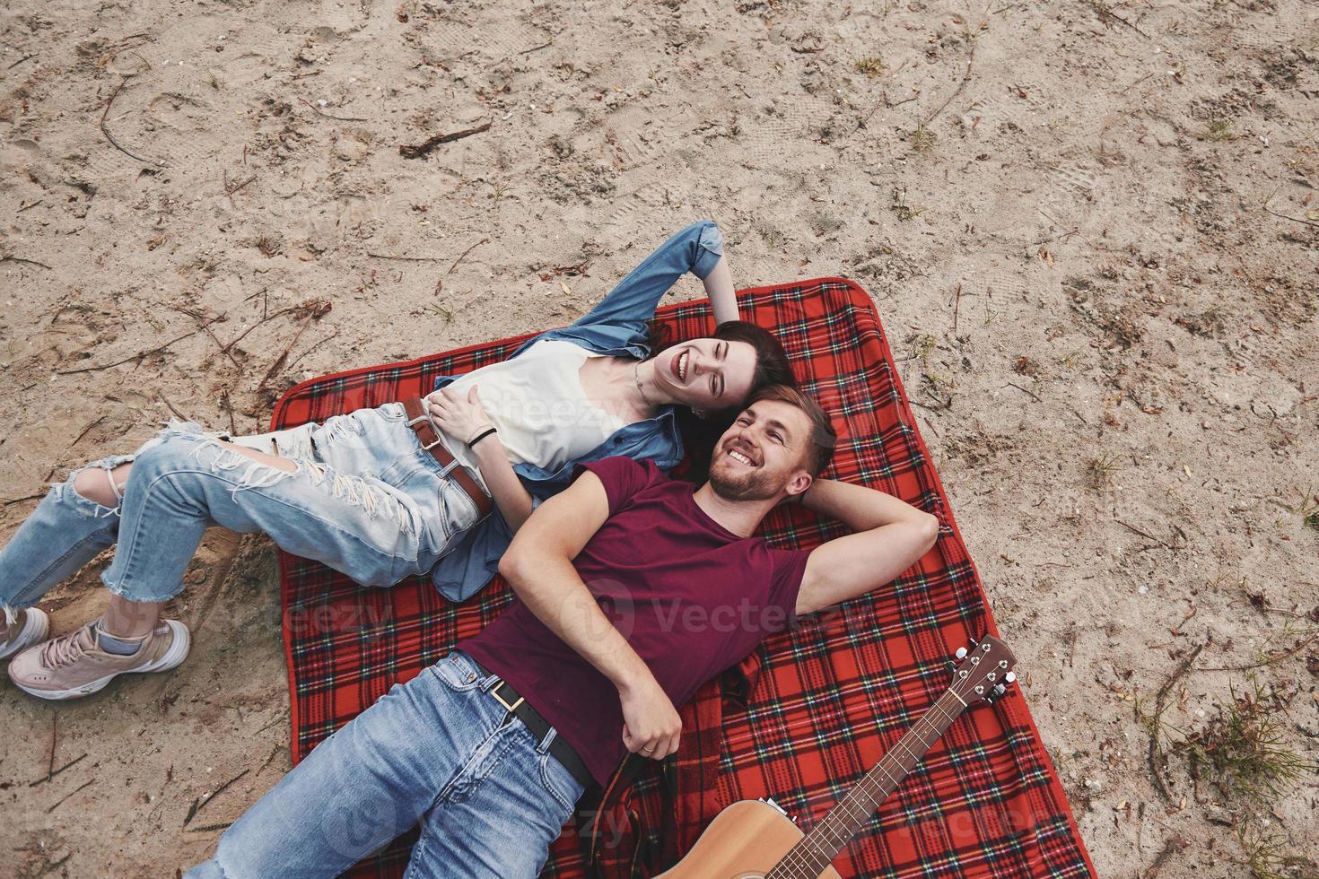 top visie. jong paar hebben picknick Aan de strand. aan het liegen Aan de rood gekleurde deken foto