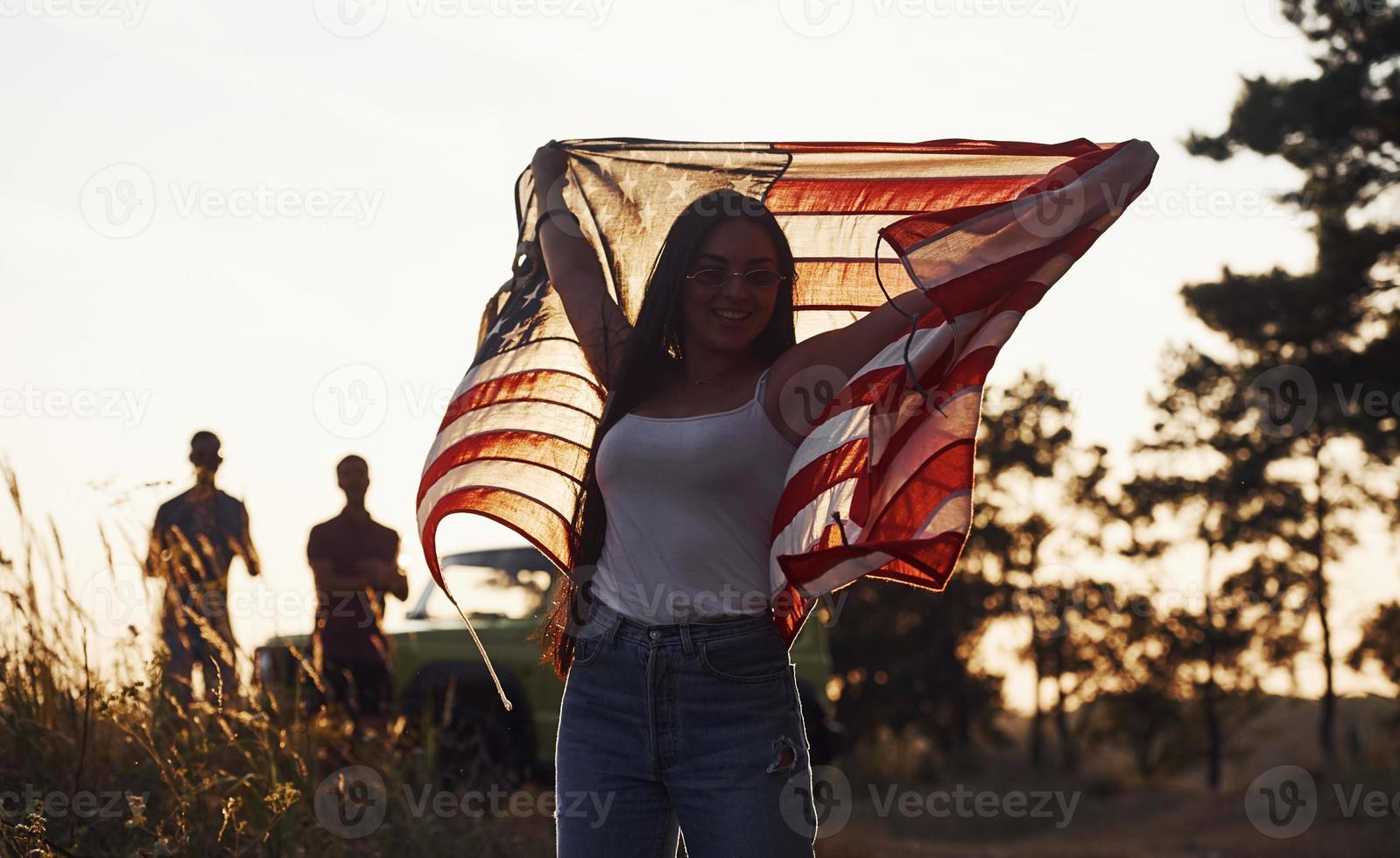 voelt vrijheid. vrienden hebben mooi hoor weekend buitenshuis in de buurt van hen groen auto met Verenigde Staten van Amerika vlag foto