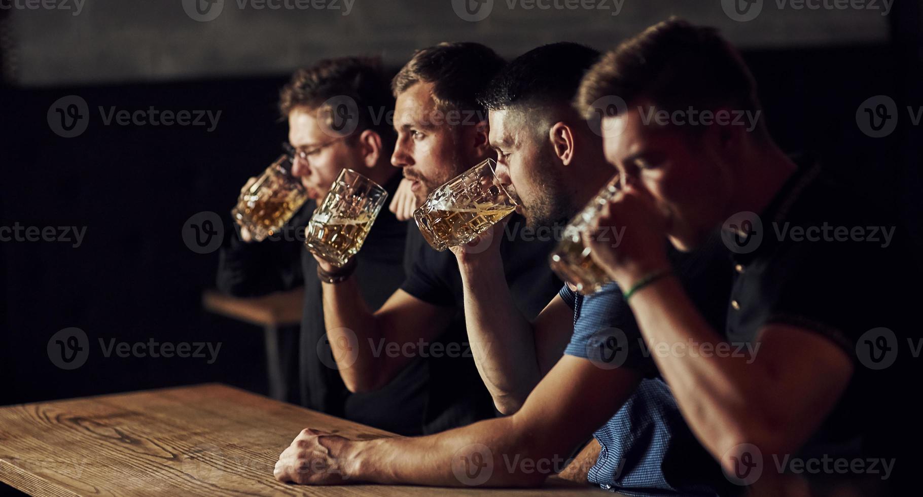 drinken bier. drie sport- fans in een bar aan het kijken voetbal foto