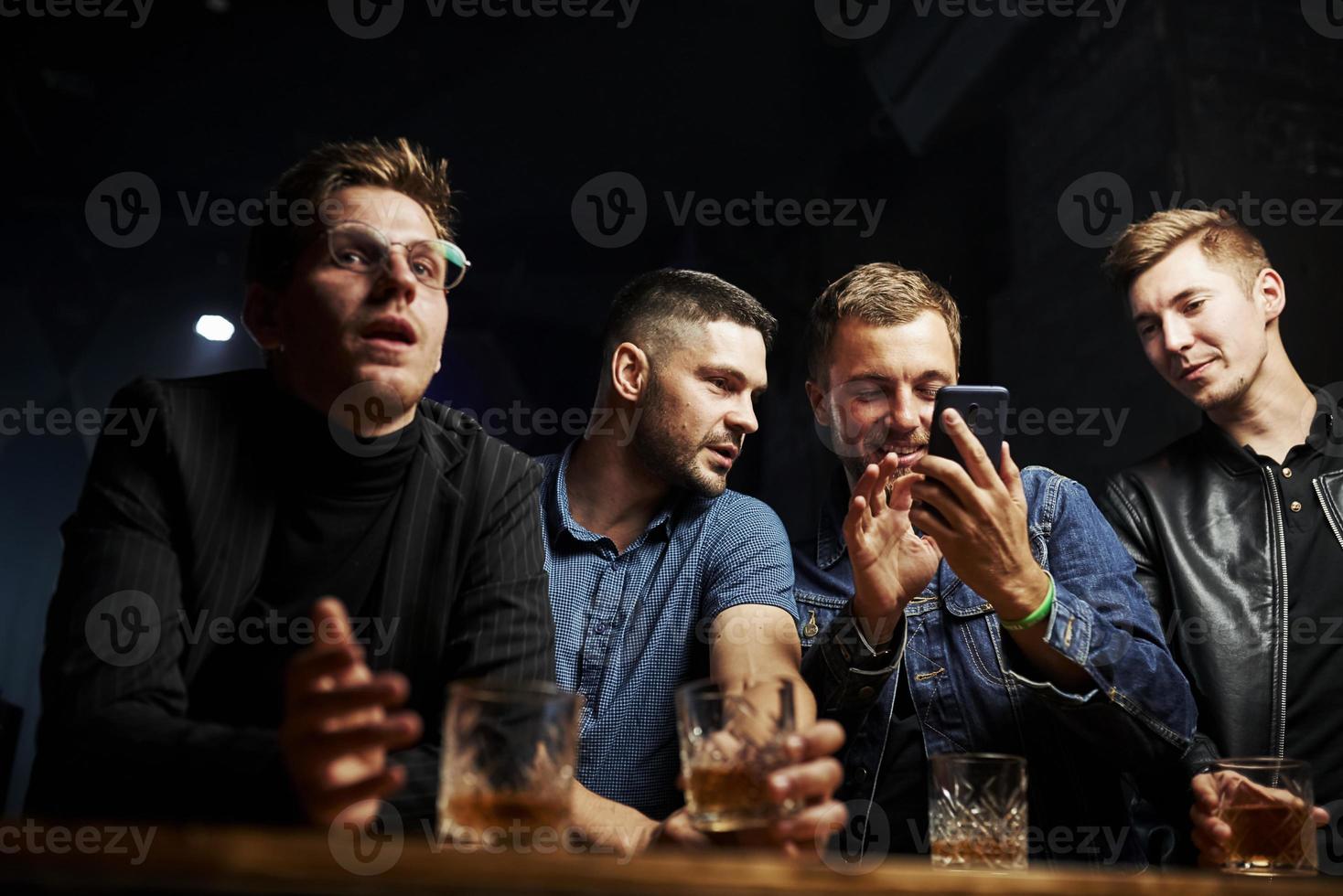 voorkant visie. vrienden resting in de kroeg met alcohol in handen. hebben gesprek foto