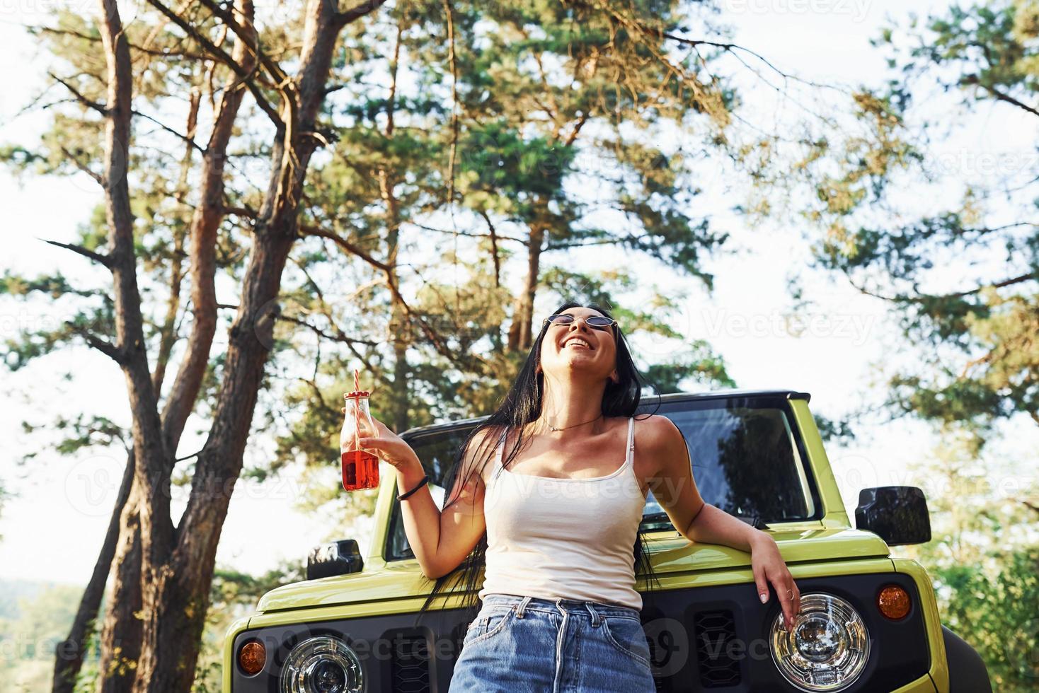 blond met alcohol in hand- hebben een wandelen in de Woud tegen groen jeep foto