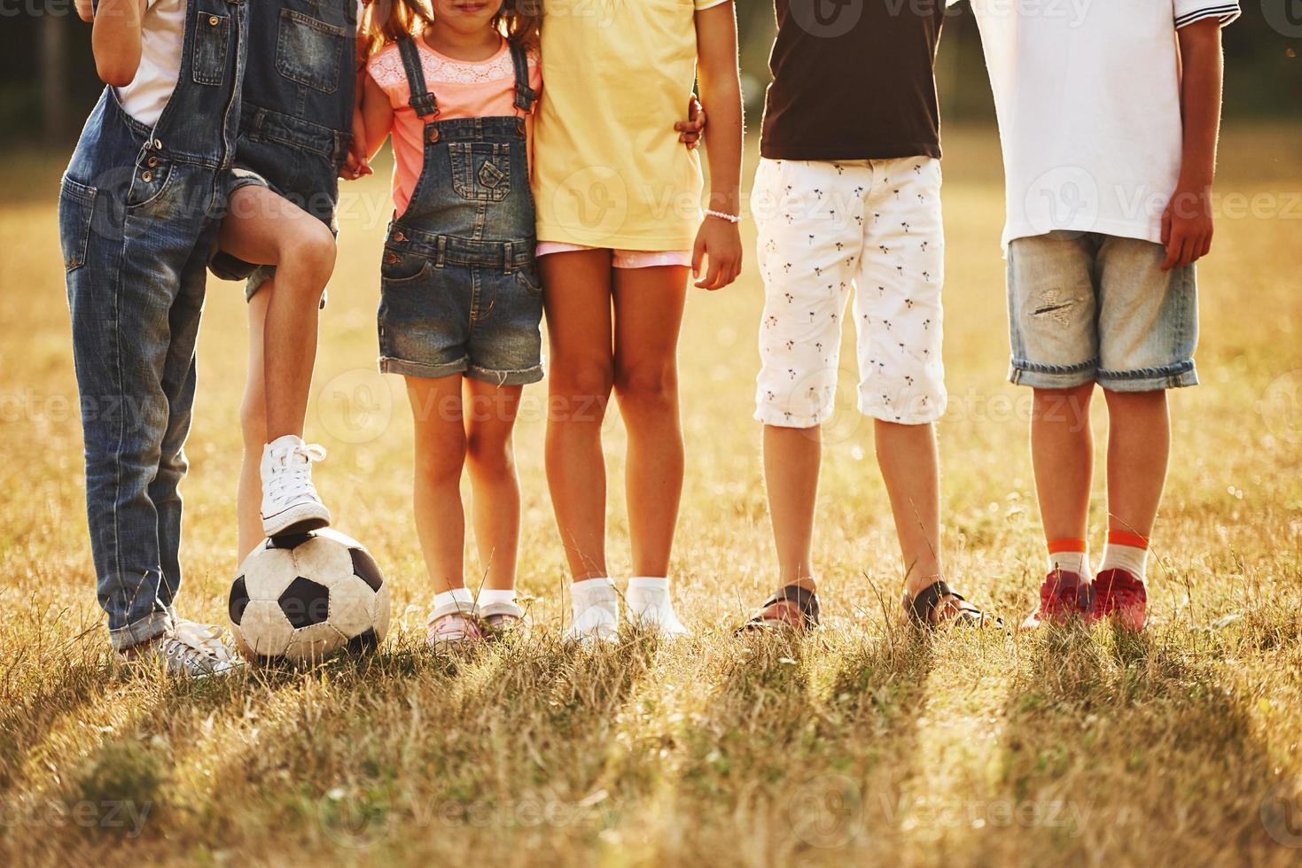 deeltje visie van sportief kinderen met voetbal bal staat samen in de veld- Bij zonnig dag foto