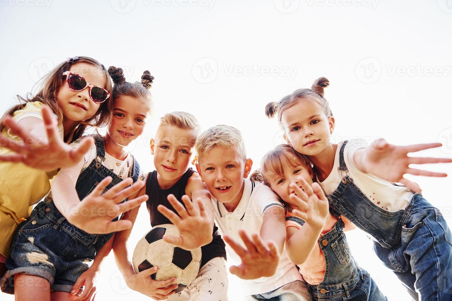 Hallo, gebaar. met voetbal bal. portret van kinderen dat staand samen en poseren voor de camera foto