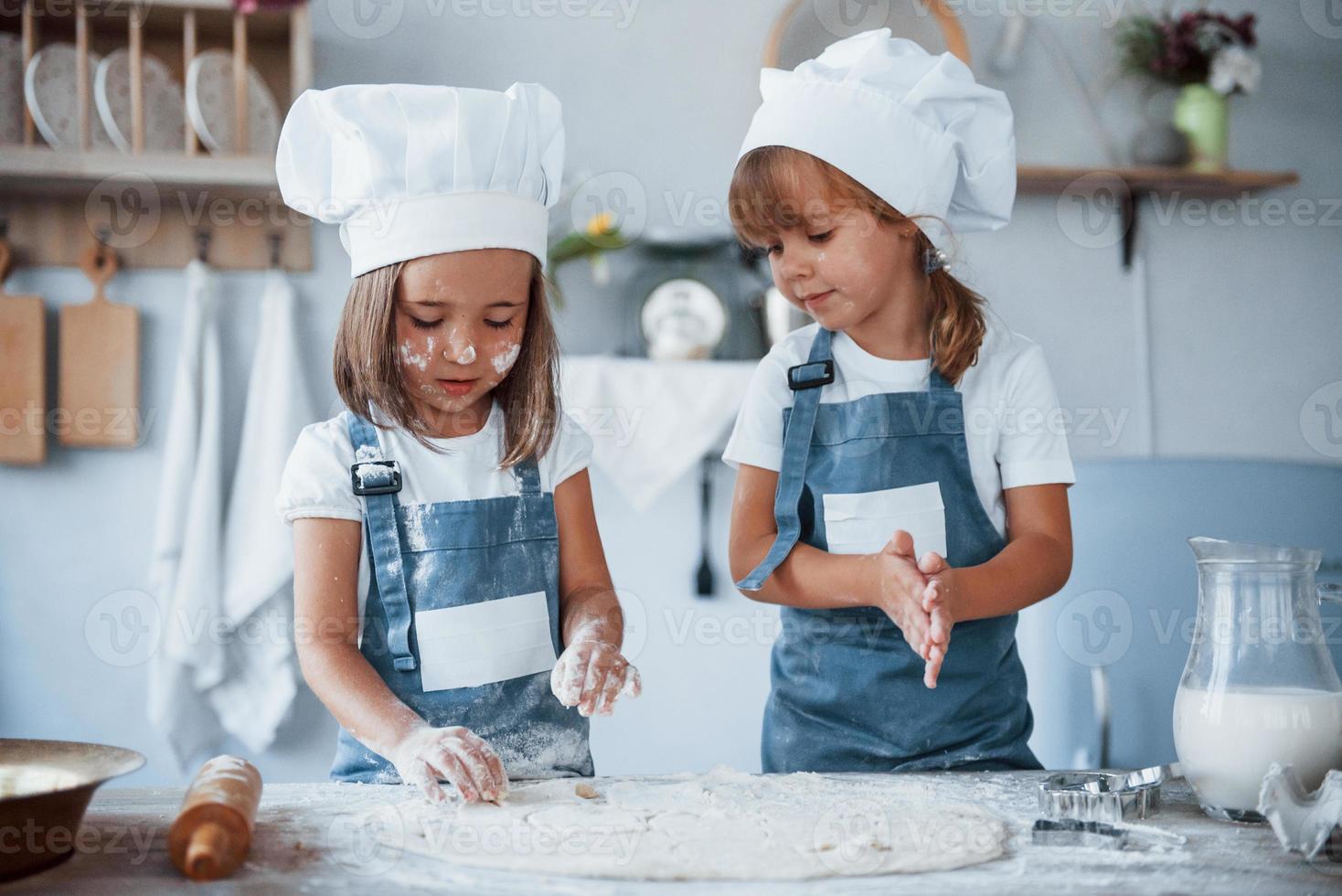 concentreren Bij Koken. familie kinderen in wit chef uniform voorbereidingen treffen voedsel Aan de keuken foto