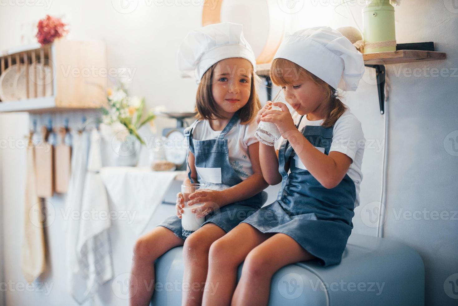 zittend Aan de koelkast. familie kinderen in wit chef uniform eet voedsel Aan de keuken foto