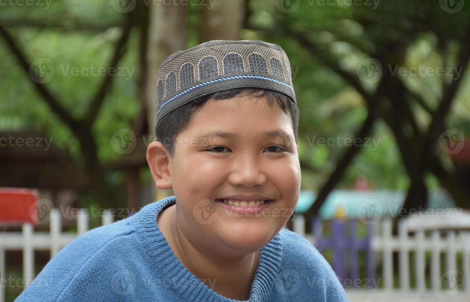 portret Aziatisch moslim of Islamitisch jongen zittend in de school- park en glimlachen gelukkig, zacht en selectief focus. foto