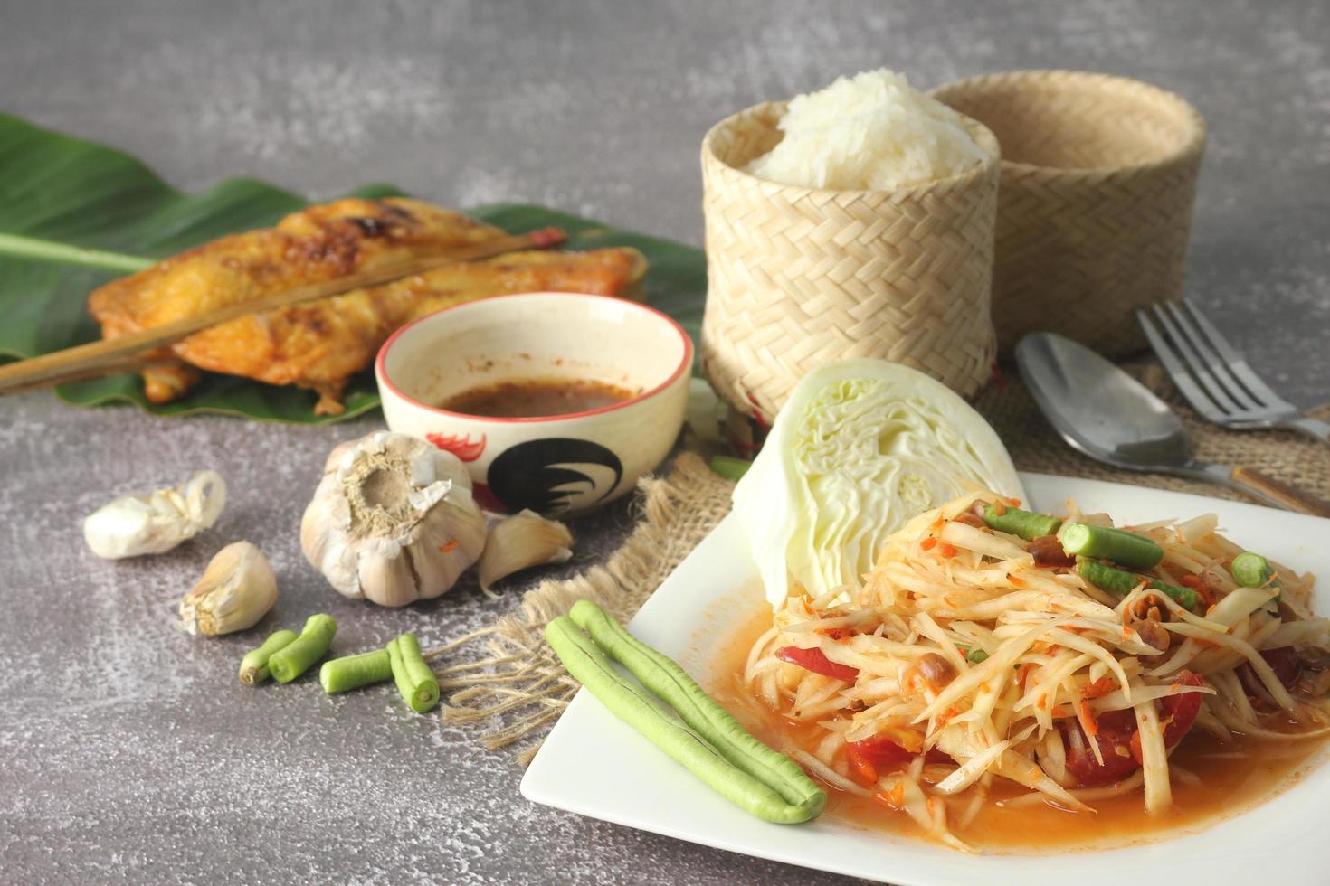 papaja salade, populair Thais voedsel geserveerd met gegrild kip, kleverig rijst- en lang bonen. foto