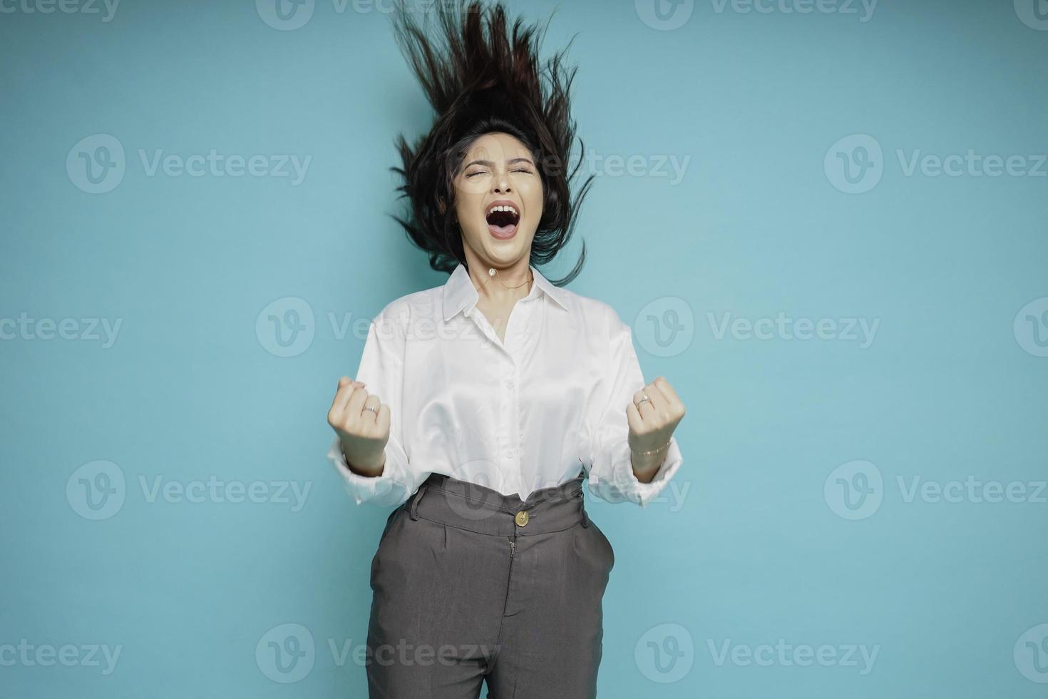 een jong Aziatisch vrouw met een gelukkig geslaagd uitdrukking vervelend wit overhemd geïsoleerd door blauw achtergrond foto