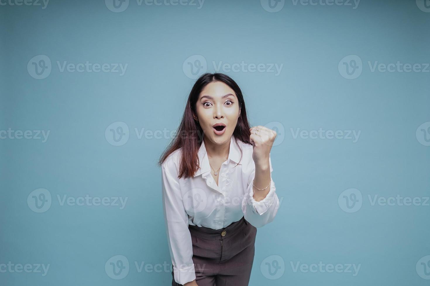 een jong Aziatisch vrouw met een gelukkig geslaagd uitdrukking vervelend wit overhemd geïsoleerd door blauw achtergrond foto