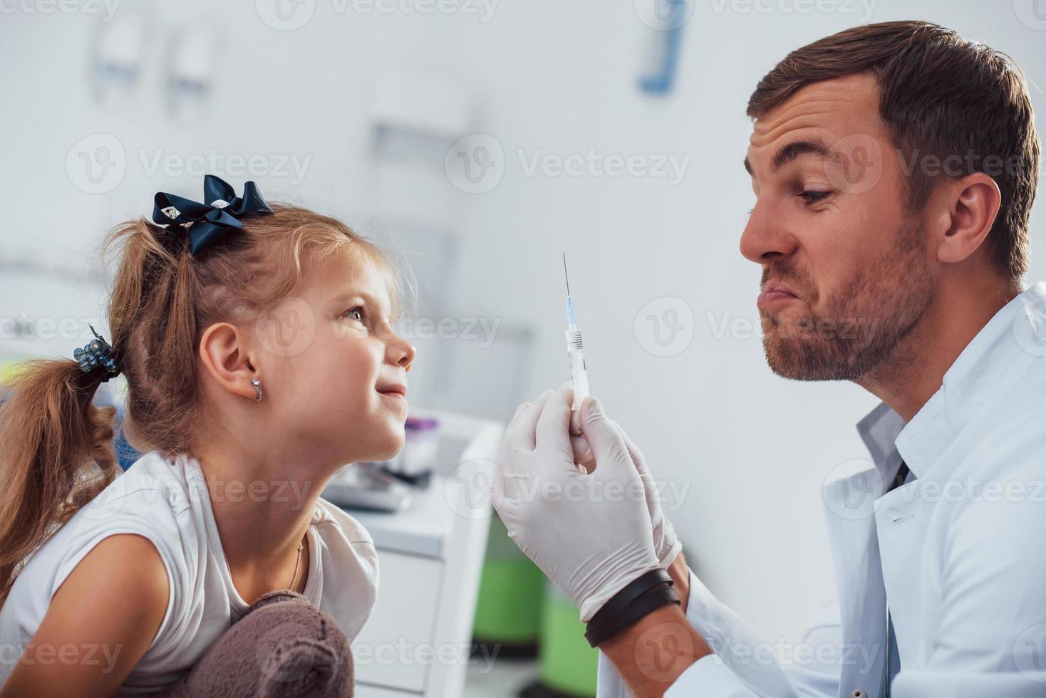 bloed bemonstering. weinig meisje met haar teddy beer is in de kliniek met dokter foto