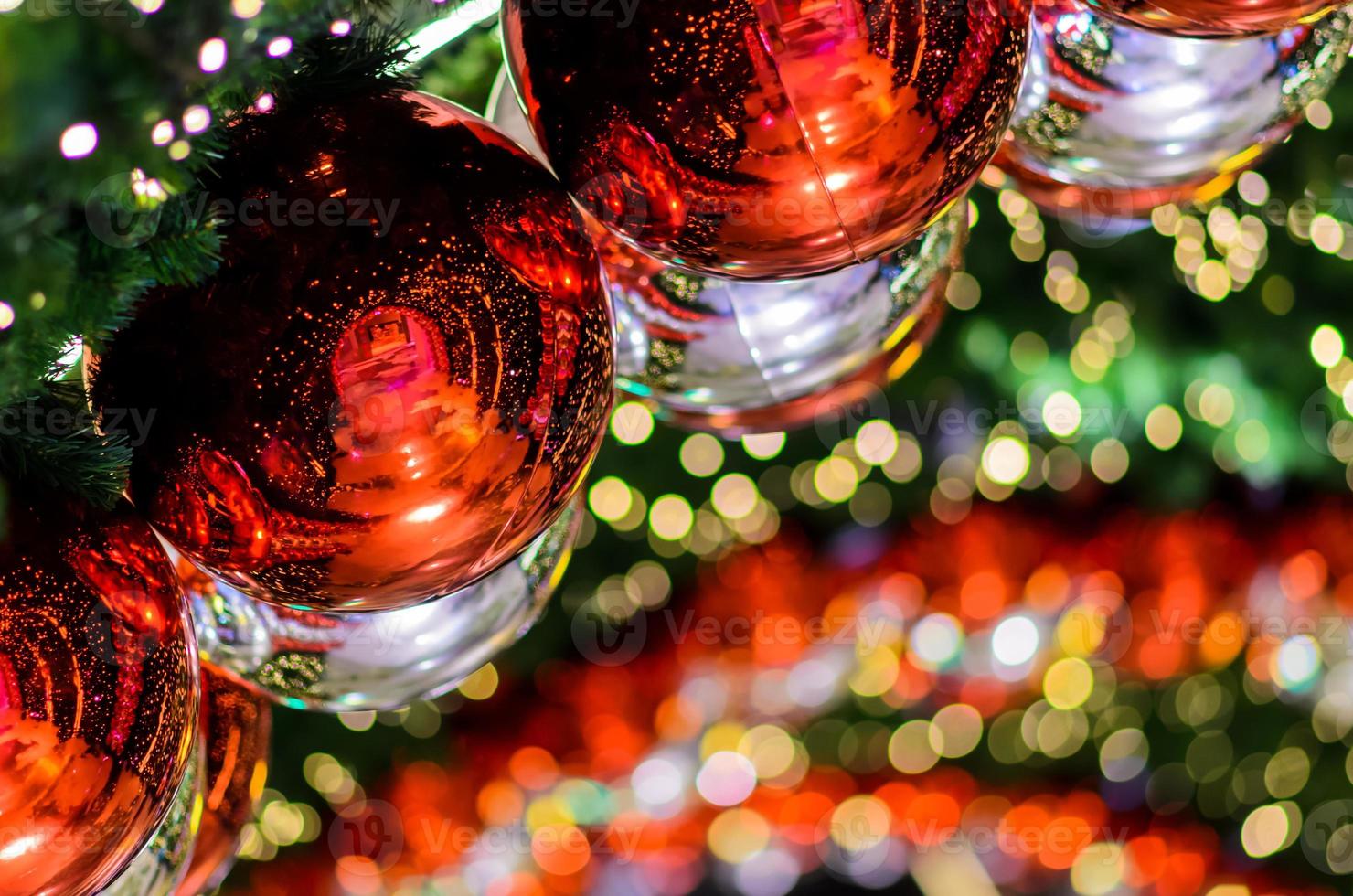 rood snuisterij en andere ornament hangende Aan Kerstmis boom met bokeh licht achtergrond. foto