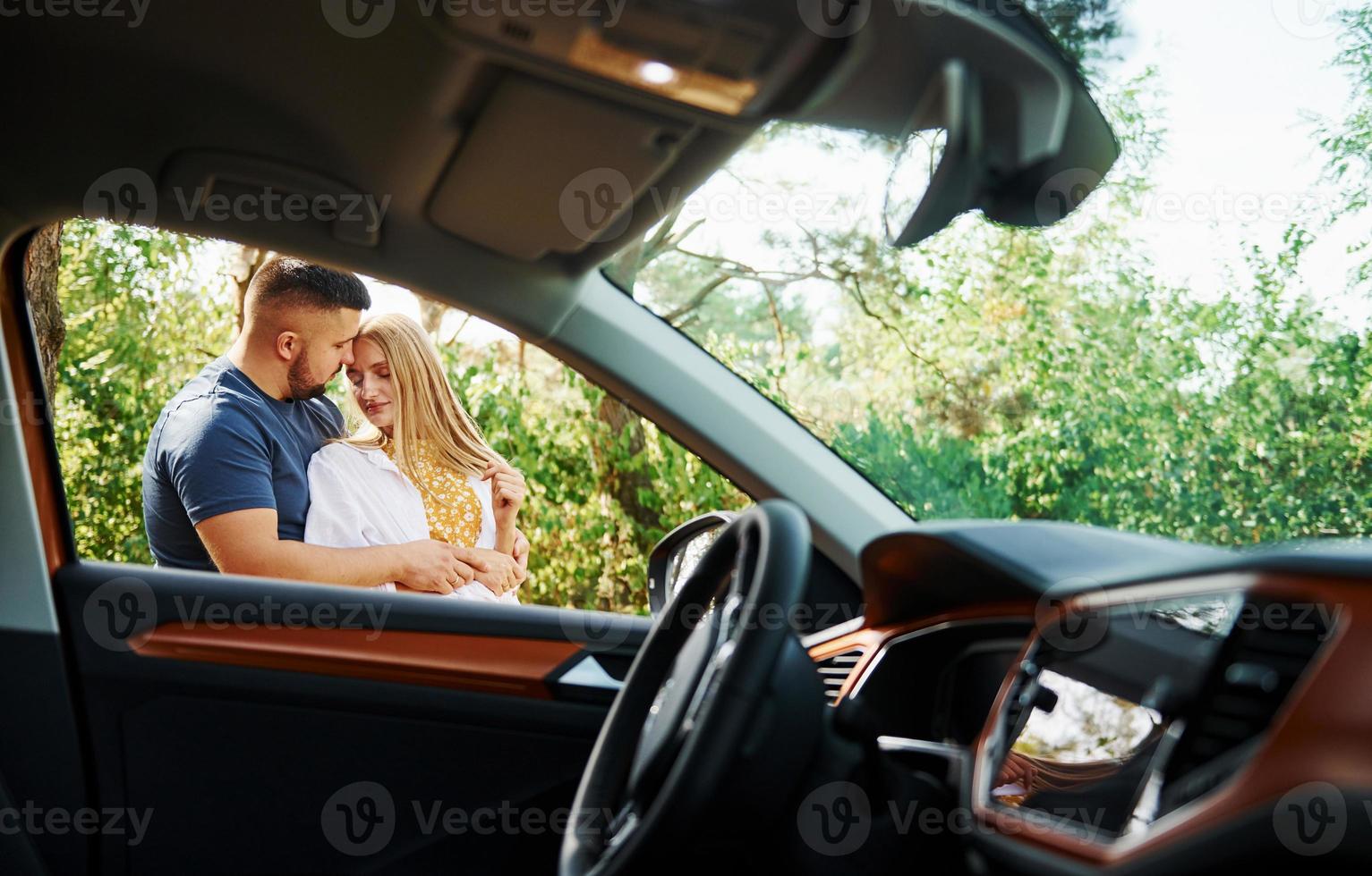 interieur van voertuig. paar omarmen elk andere in de Woud in de buurt modern auto foto