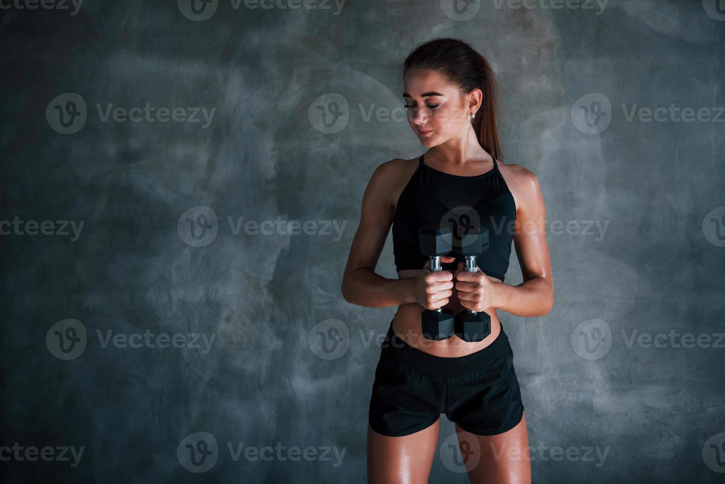 jong geschiktheid vrouw is in de Sportschool in de buurt muur met halters in handen foto