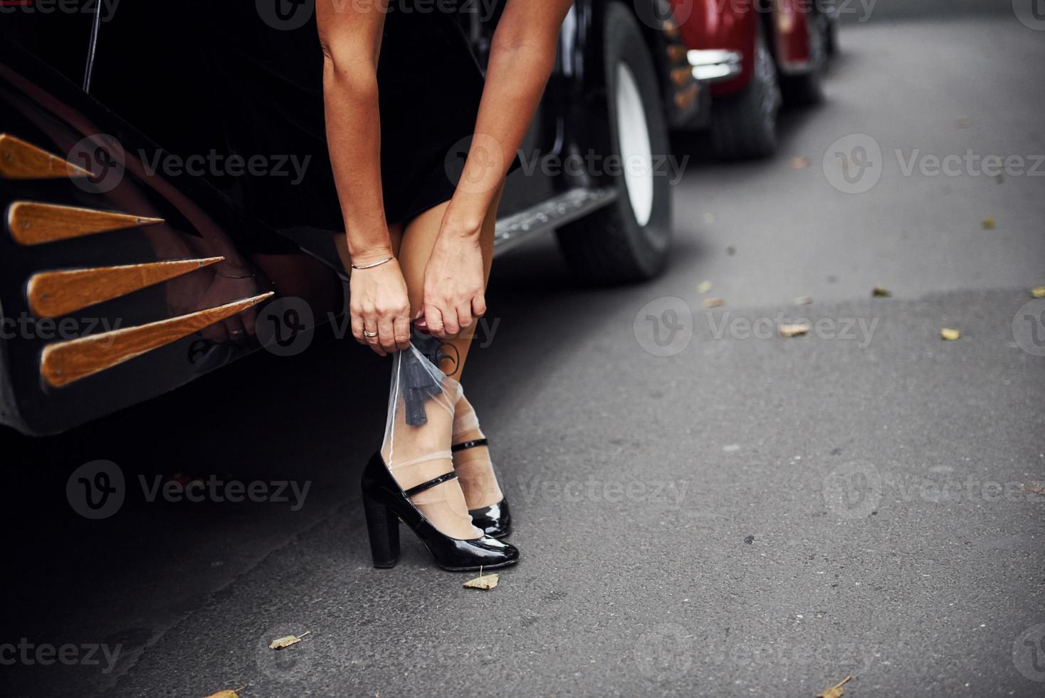 dichtbij omhoog visie van vrouw poten in de buurt oud fashioned auto. met geweer in hand- foto