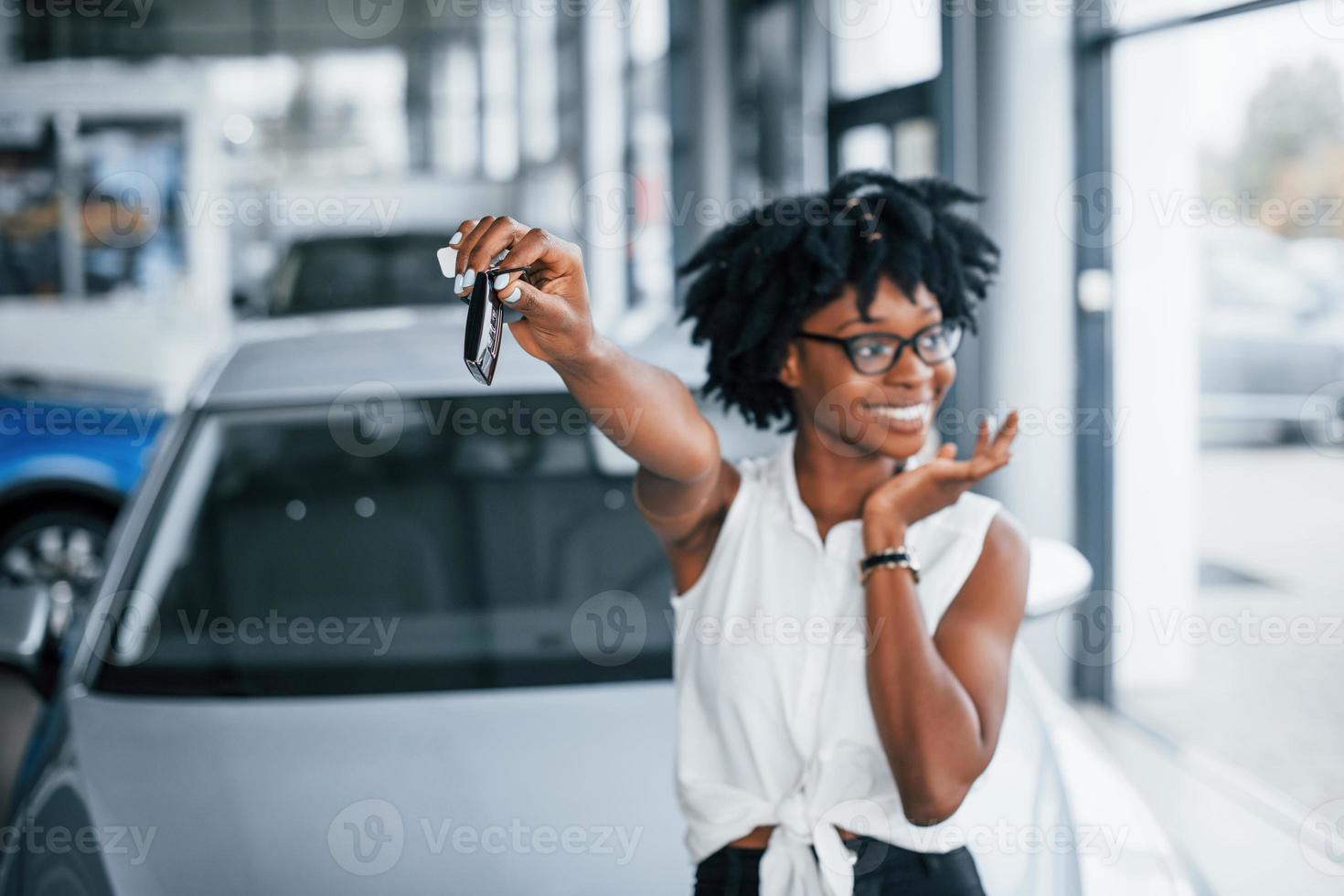 jong Afrikaanse Amerikaans vrouw in bril staat binnenshuis met sleutels in handen foto