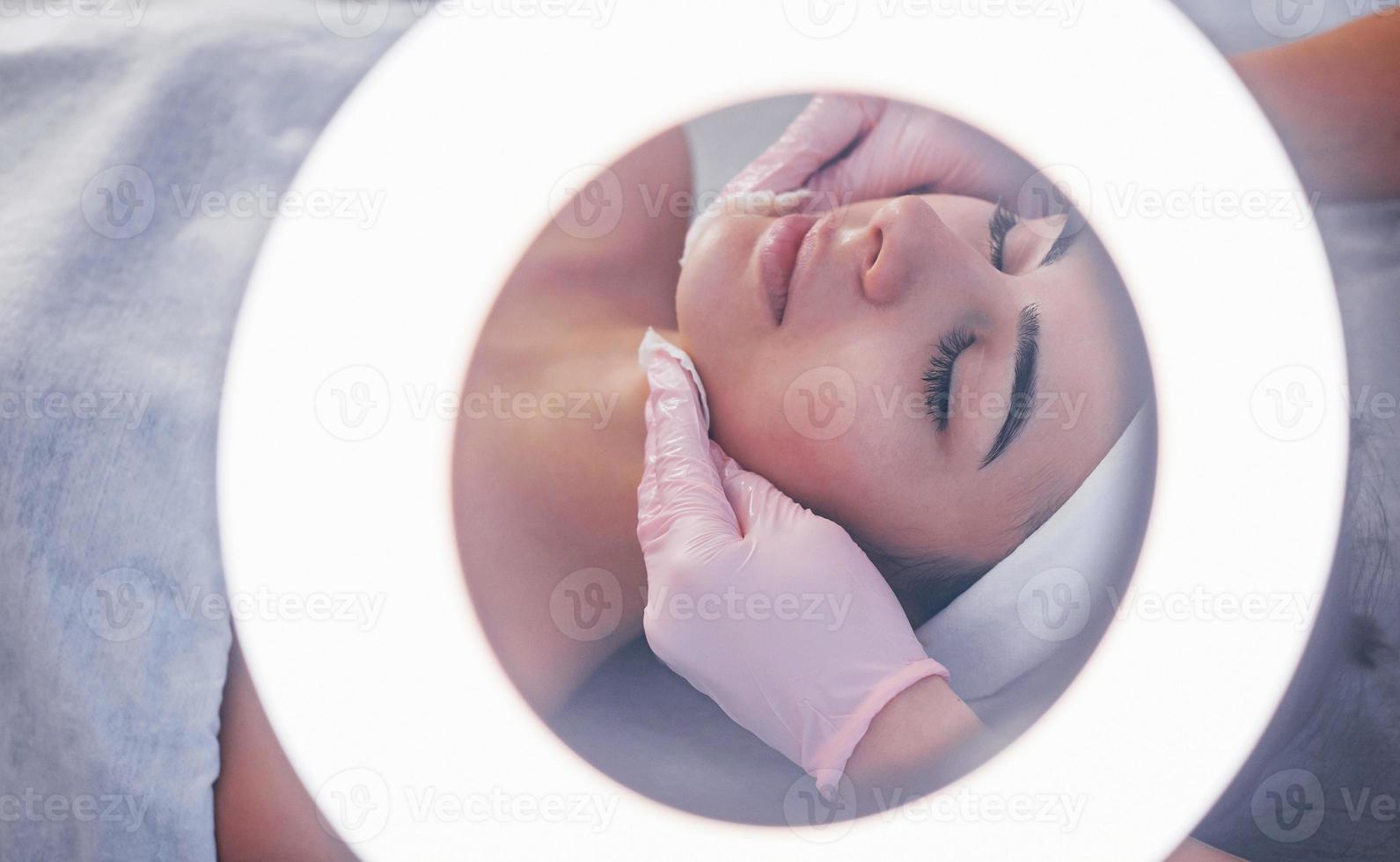 dichtbij omhoog visie van vrouw dat aan het liegen naar beneden in spa salon en hebben gezicht schoonmaak procedure foto