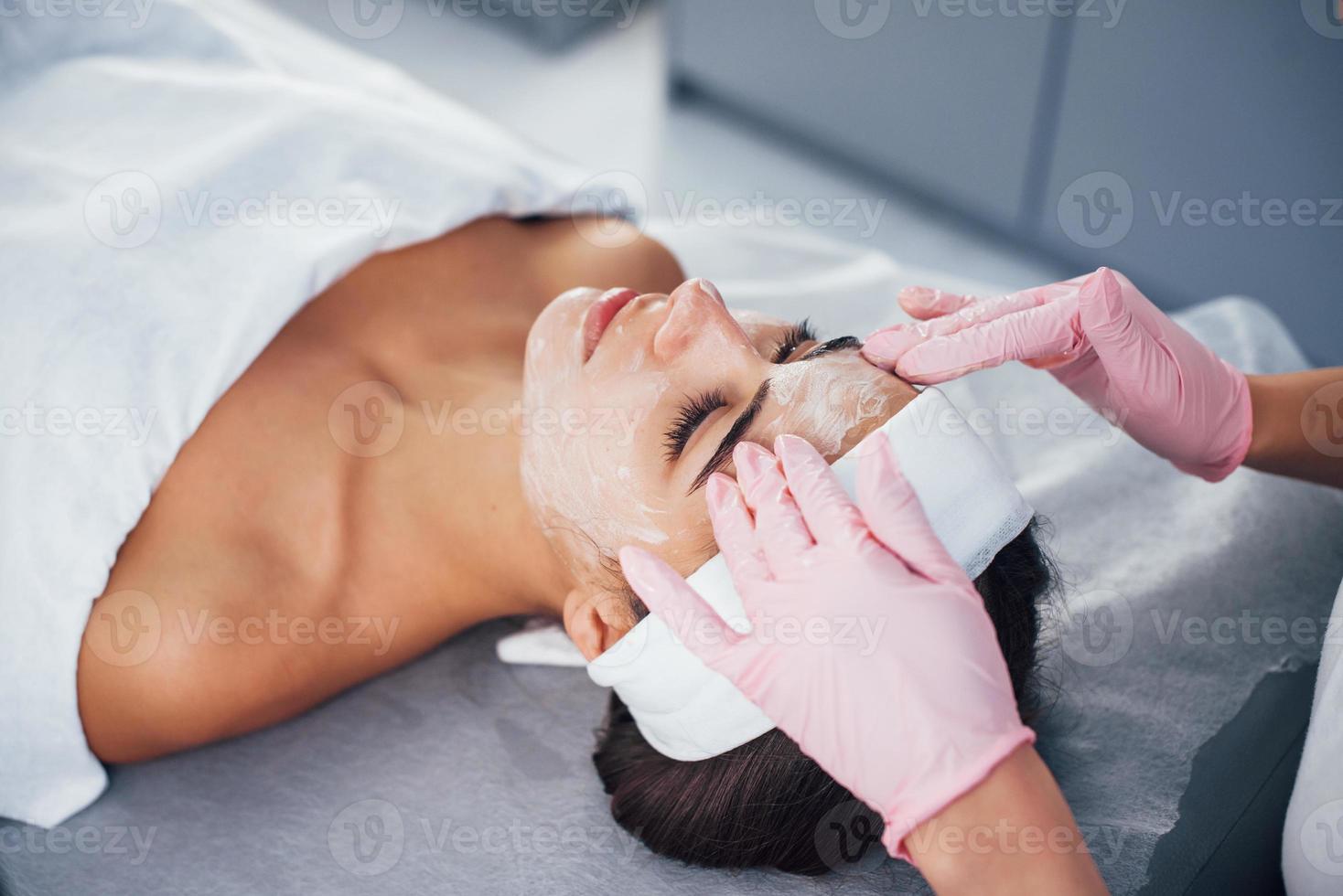 dichtbij omhoog visie van vrouw dat aan het liegen naar beneden in spa salon en hebben gezicht schoonmaak procedure door de masker foto