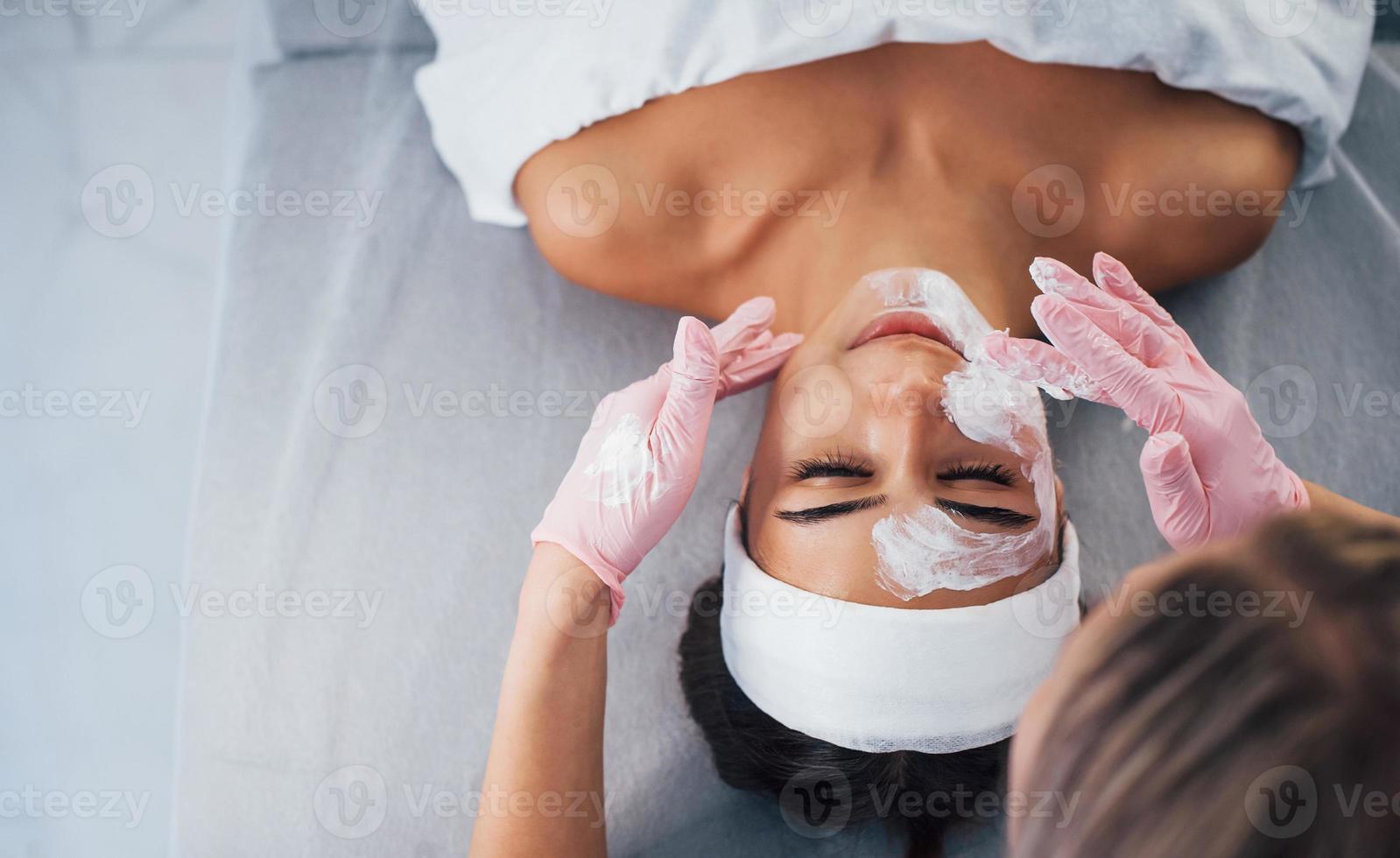 dichtbij omhoog visie van vrouw dat aan het liegen naar beneden in spa salon en hebben gezicht schoonmaak procedure door de masker foto