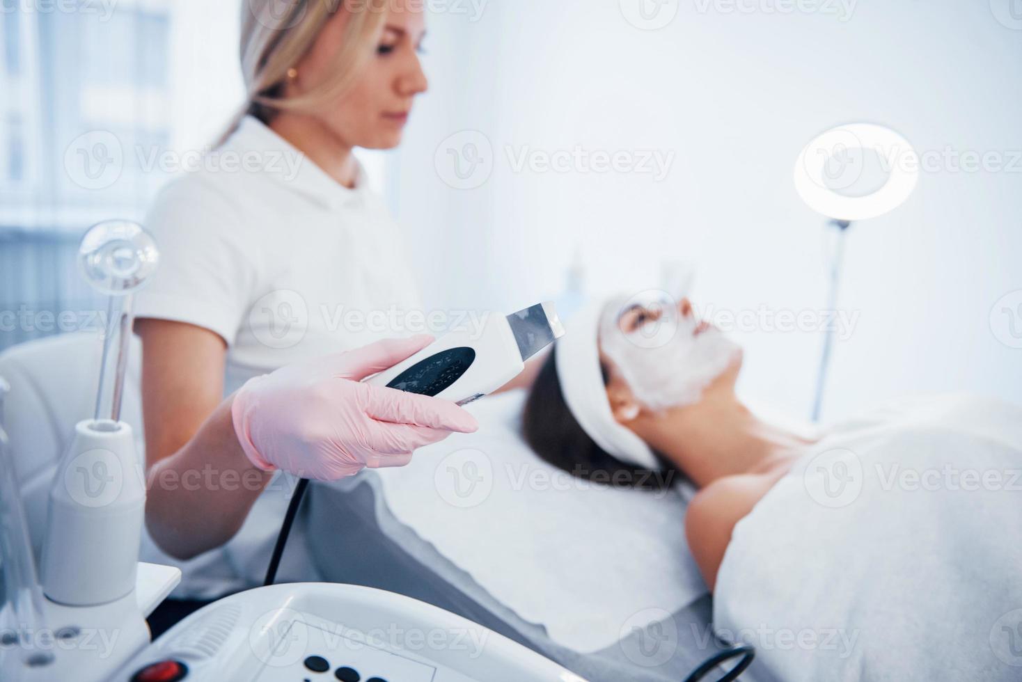 vrouw aan het liegen naar beneden in spa salon en hebben gezicht schoonmaak procedure door professioneel schoonheidsspecialist foto