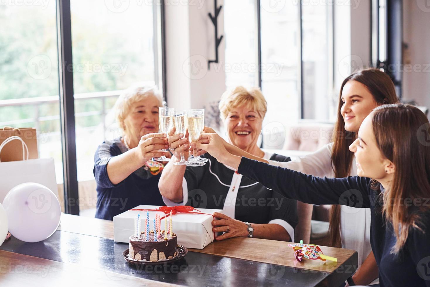 kloppen bril. senior vrouw met familie en vrienden vieren een verjaardag binnenshuis foto