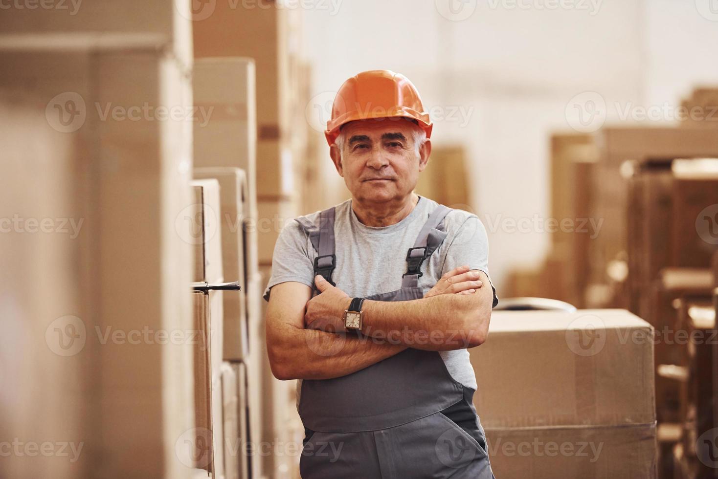 portret van senior opslagruimte arbeider in magazijn in uniform en moeilijk hoed foto