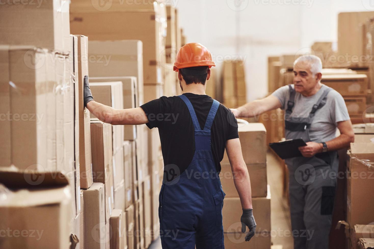 jong en senior opslagruimte arbeiders in uniform werken samen in de magazijn foto