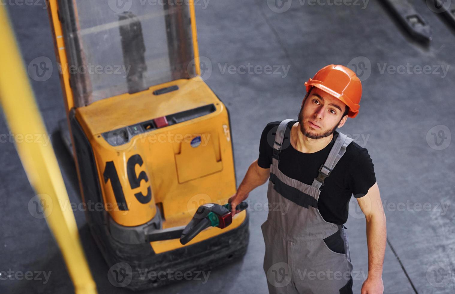 jong mannetje arbeider in uniform is in de magazijn voortvarend pallet vrachtauto foto