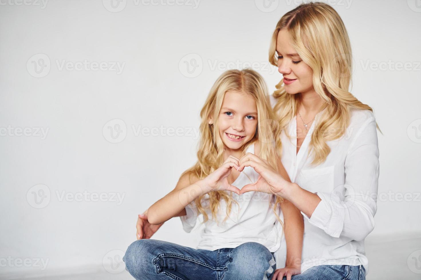 moeder met haar dochter samen shows liefde gebaar in de studio met wit achtergrond foto