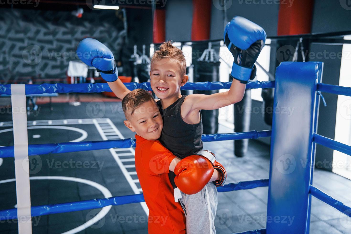 portret van twee jong jongens in beschermend handschoenen vieren zege Aan boksen ring foto