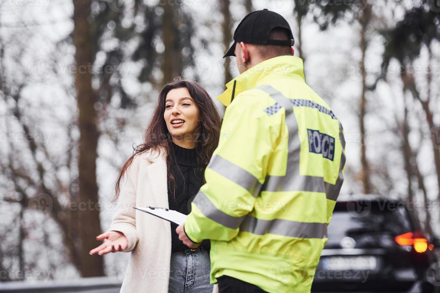 mannetje Politie officier in groen uniform pratend met vrouw eigenaar van de auto Aan de weg foto