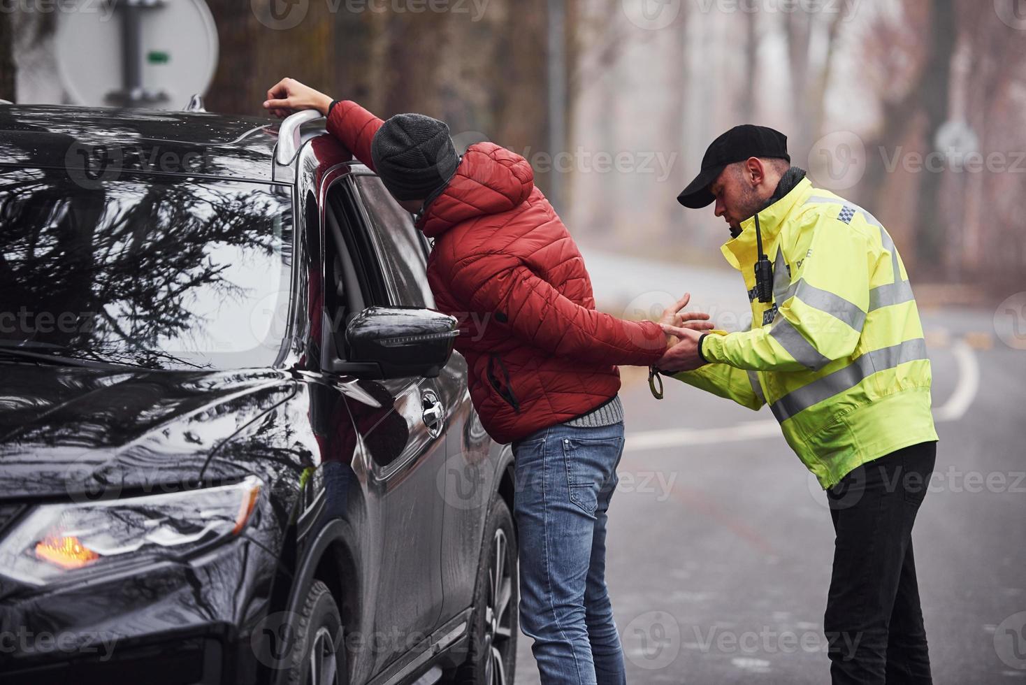 Politie officier in groen uniform gevangen auto- diefstal Aan de weg foto