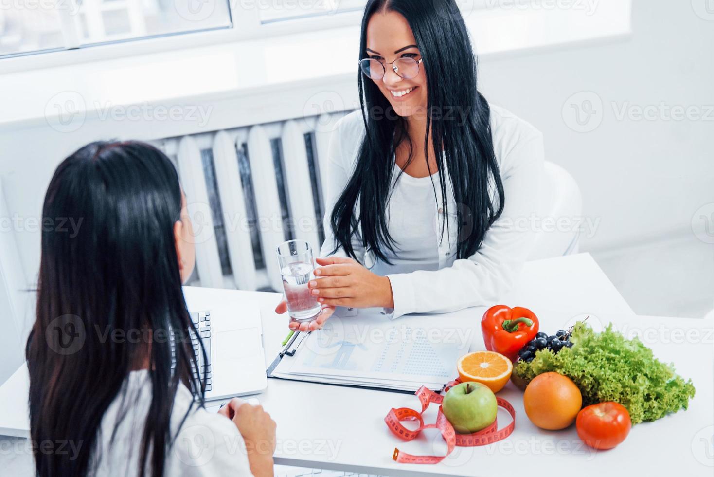 vrouw voedingsdeskundige geeft overleg naar geduldig binnenshuis in de kantoor foto