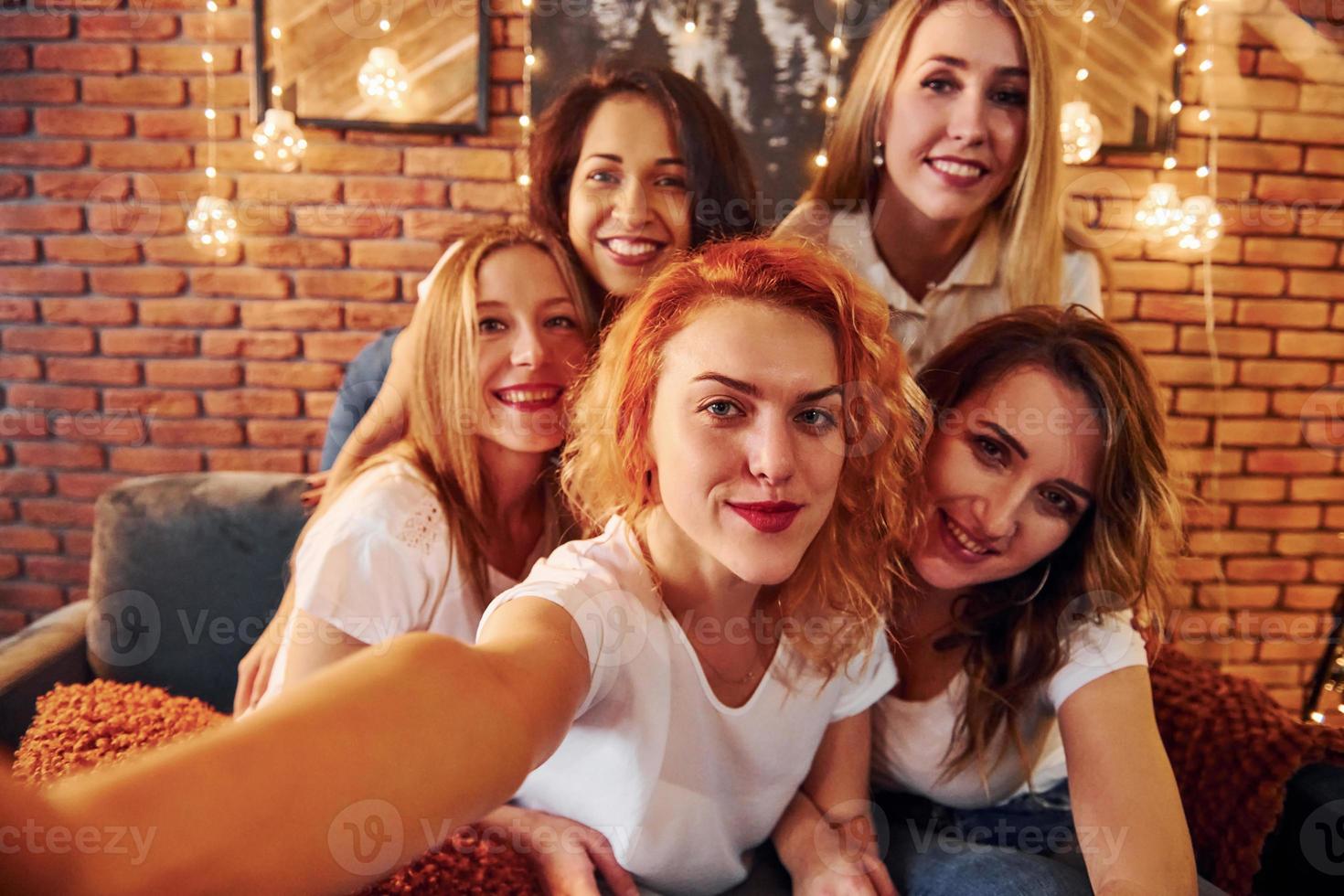 vrolijk Dames nemen selfie en vieren nieuw jaar vakantie binnenshuis van Kerstmis versierd kamer foto